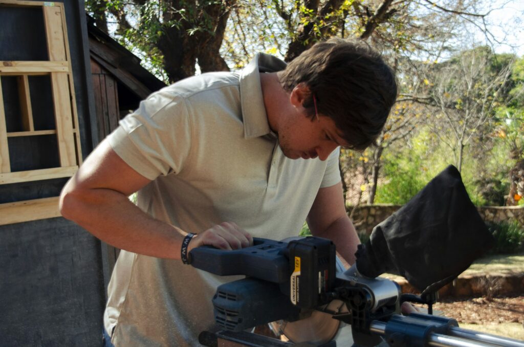 Man cutting wood with a circular saw outside his workshop