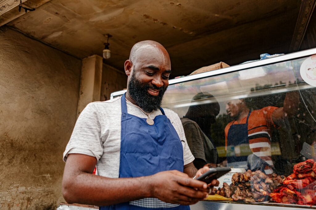 Small business owner in an apron at his shop counter, checking his phone