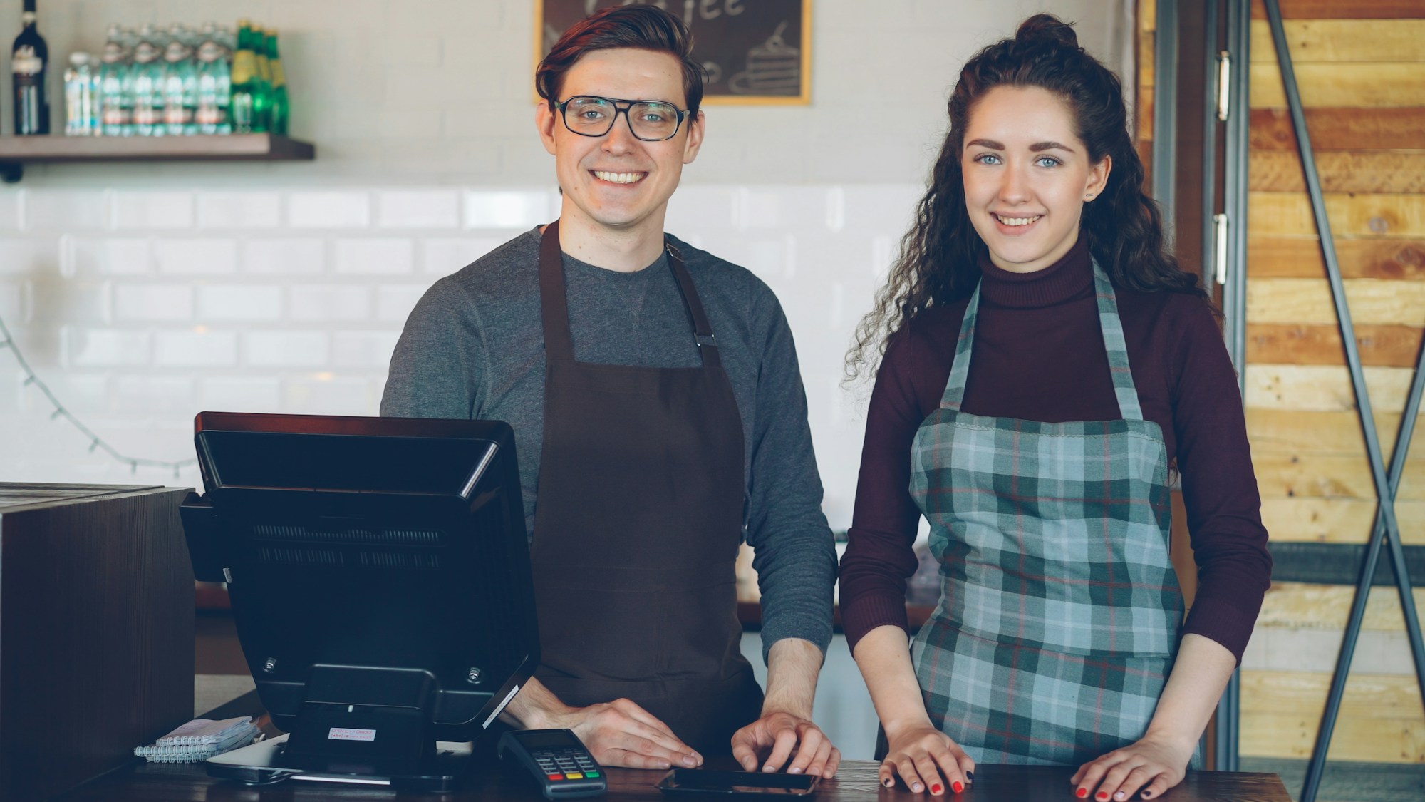 Two cafe owners standing behind the counter of their coffee shop